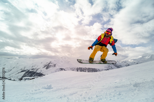 Snowboarder at jump inhigh mountains at sunny day.