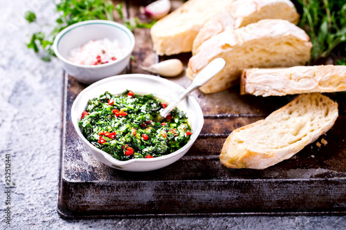  Argentinian green Chimichurri with ingredients.Raw homemade with ciabatta.Salsa or sauce made of parsley, garlic, oregano, hot pepper, olive oil, vinegar.Food Concept.