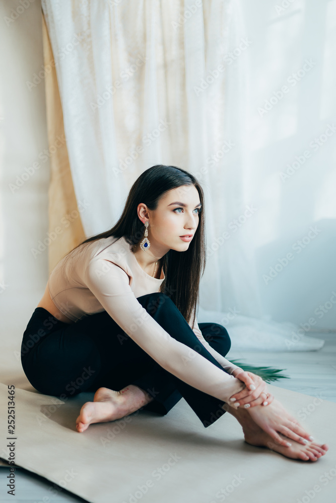 young beautiful brunette girl posing in the studio, dressed in black pants, blouse. piercing gaze