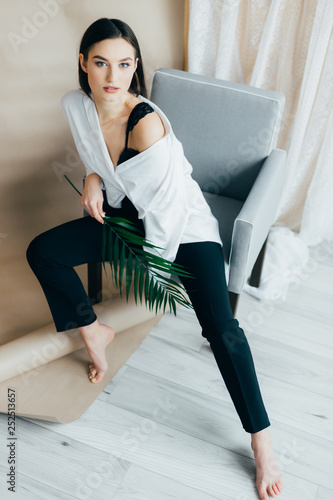 young beautiful brunette girl posing in the studio, dressed in black pants, blouse. piercing gaze