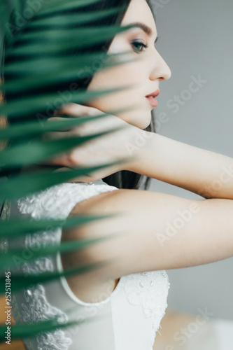 beautiful tender young girl, with flowers, dressed in a light dress, in a studio with natural light. posing, smiling, piercing gaze