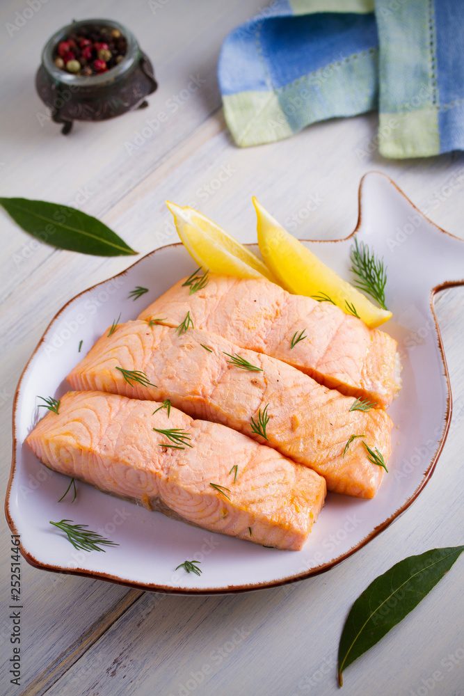 Cooked on steam salmon steaks with lemon. Dietary menu. White plate on white table. vertical Cooked on steam salmon steaks with lemon. Dietary menu. White plate on white table. vertical