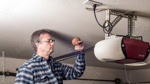 Obraz na płótnie Homeowner applies a little lubricating oil to the chain on his garage door opene