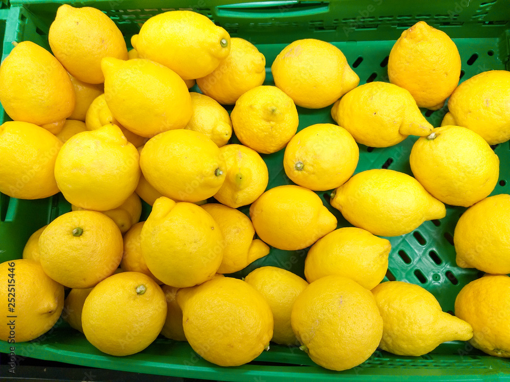 plastic green box at the market plenty of heap yellow lemons ready to be sold to customers.