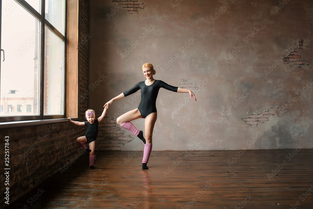 mom and daughter three years in gymnastic black swimwear and pink leggings show elements of gymnastics