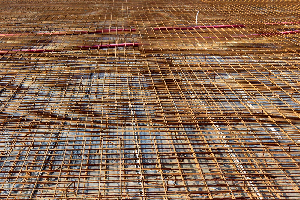 Fototapeta premium Densely laid rusted metal construction net on top of strong concrete foundation at local building construction site on warm sunny day