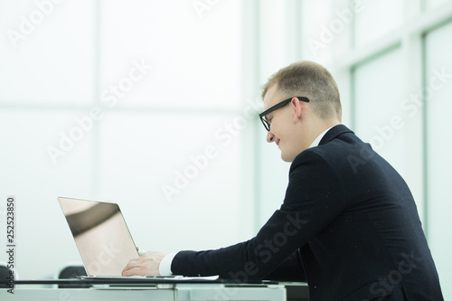 smiling businessman working on laptop in office.