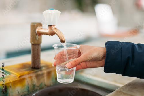 Yessentuki, Stavropol Territory / Russia - February 26, 2019: Drinking gallery of mineral spring Essentuki № 4. indoors. close - up of young woman gaining glass of mineral water from tap photo