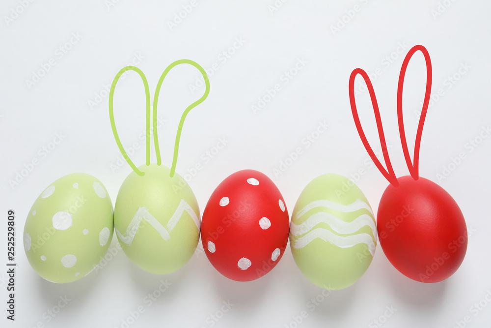 Set of colorful eggs with Easter bunny ears on light background, top view Set of colorful eggs with Easter bunny ears on light background, top view