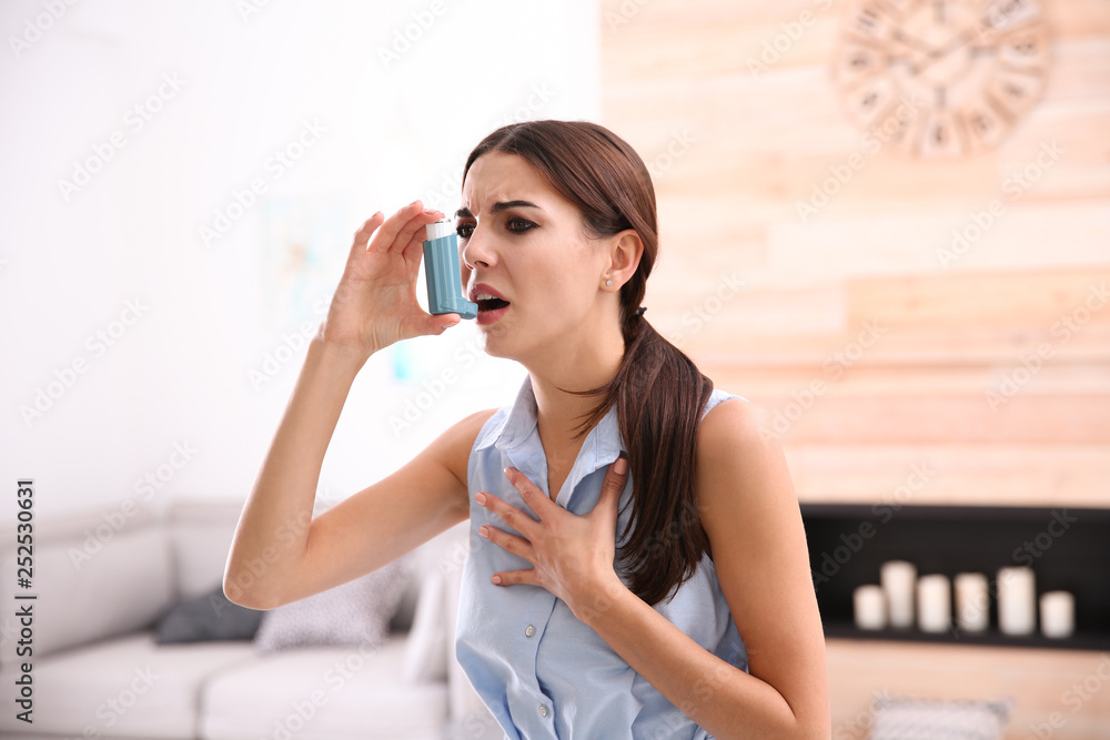 Young woman with asthma inhaler in light room Young woman with asthma inhaler in light room