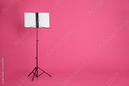 Fotografie Note stand with music sheets on color background. Space for text