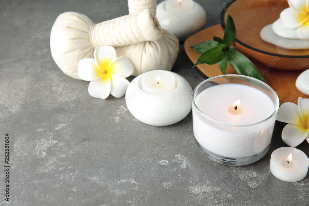 Beautiful spa composition with candles and flowers on grey background, space for text