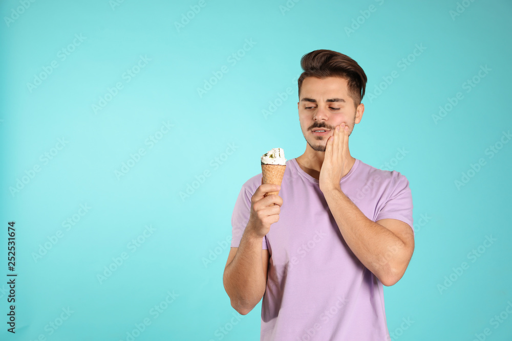 Young man with sensitive teeth and ice cream on color background. Space for text Young man with sensitive teeth and ice cream on color background. Space for text