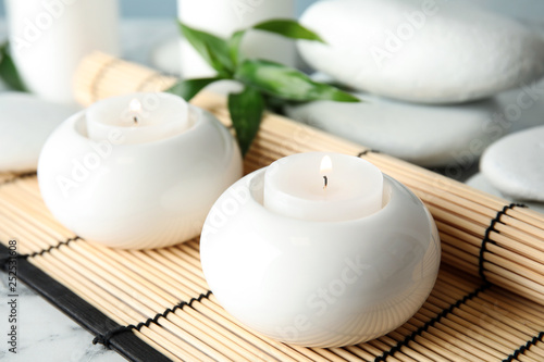 Beautiful spa composition with candles and bamboo mat on table