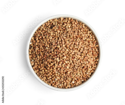 Bowl with uncooked buckwheat on white background, top view