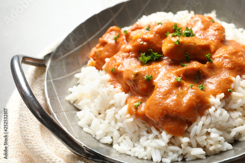 Delicious butter chicken with rice in dish and napkin on table