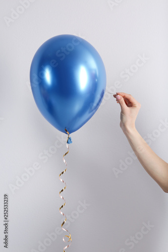 Woman piercing balloon with needle on white background, closeup