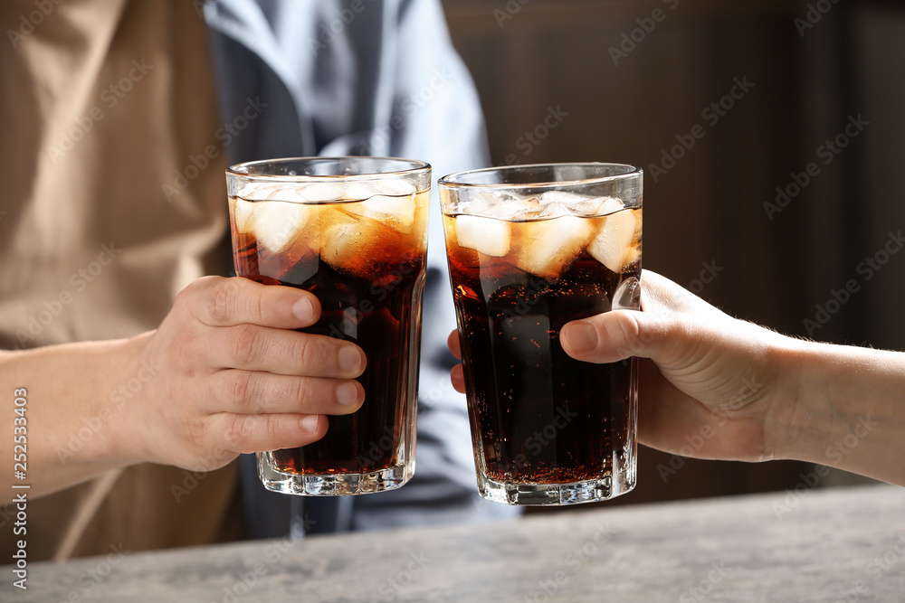 Couple with glasses of cold cola at table indoors, closeup Couple with glasses of cold cola at table indoors, closeup