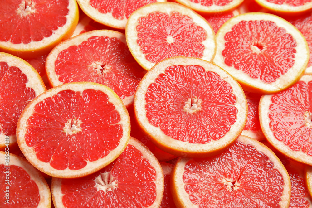 Many sliced fresh ripe grapefruits as background, closeup Many sliced fresh ripe grapefruits as background, closeup