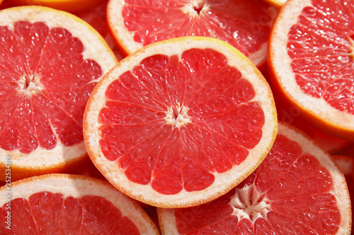 Many sliced fresh ripe grapefruits as background  closeup