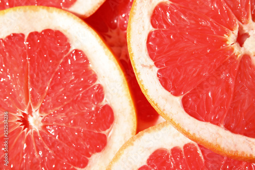 Many slices of fresh ripe grapefruits as background, closeup