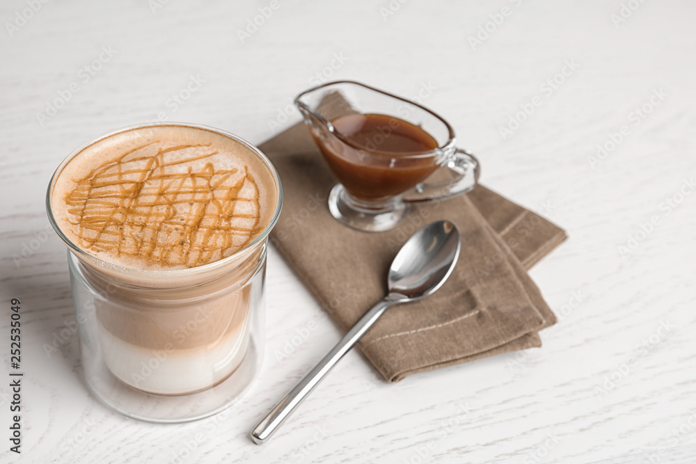 Composition with glass of caramel macchiato and gravy boat with sauce on wooden table Composition with glass of caramel macchiato and gravy boat with sauce on wooden table