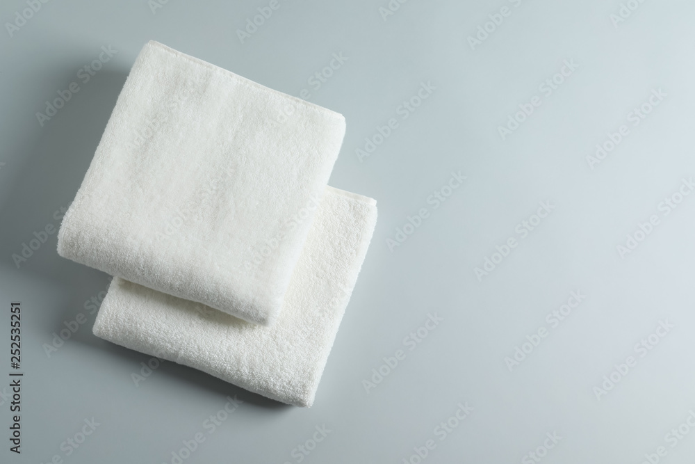 Soft folded towels on light background, top view with space for text Soft folded towels on light background, top view with space for text