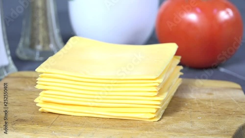 Peeling a slice of cheese off a stack of processed cheese slices
