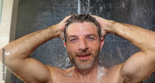 natural face portrait of young attractive and happy man at home or gym bathroom enjoying morning shower washing his hair with shampoo relaxed and cheerful