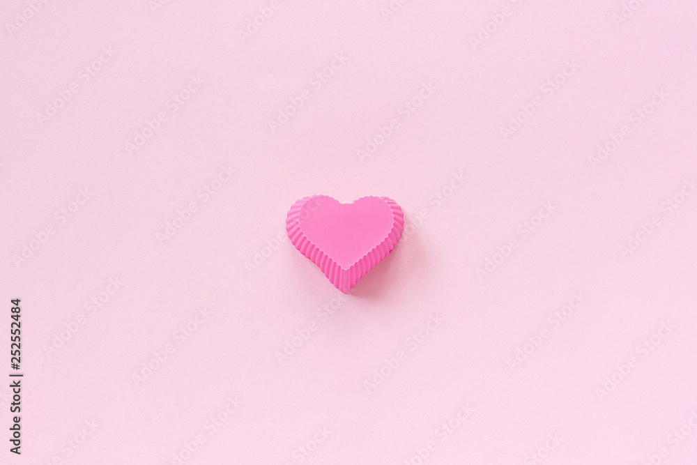 Silicone heart shaped mold dish for baking cupcakes on pink paper background. Template for lettering, text or your design Top view, copy space Minimal style