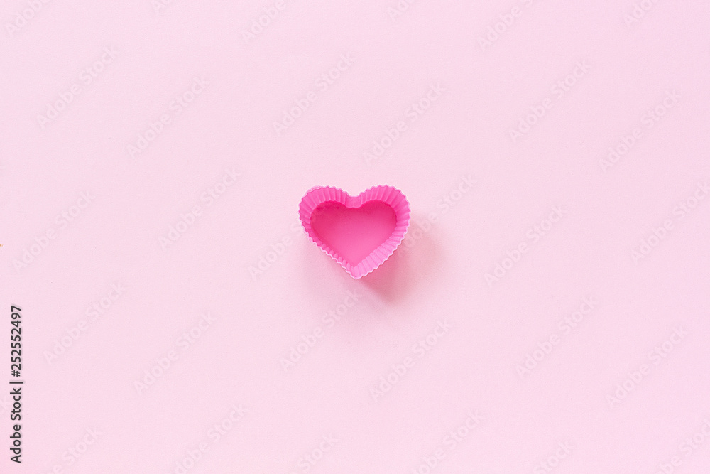 Silicone heart shaped mold dish for baking cupcakes on pink paper background. Template for lettering, text or your design Top view, copy space Minimal style