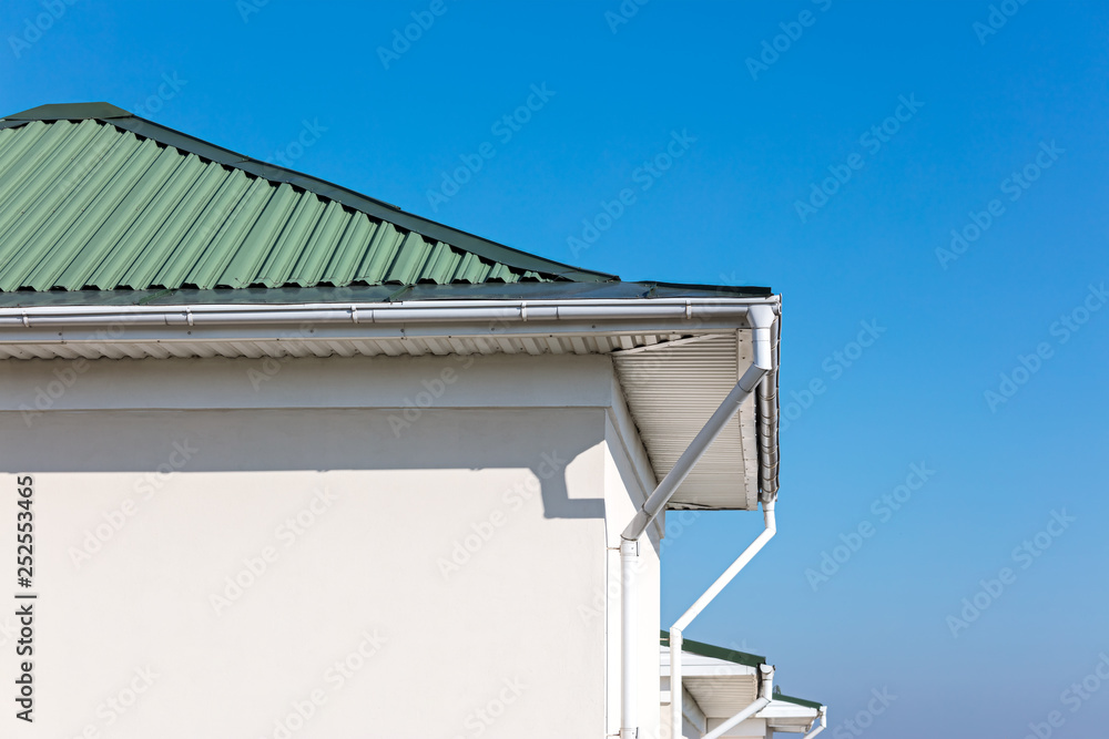 rain gutter system with downspouts on rooftop of renovated house