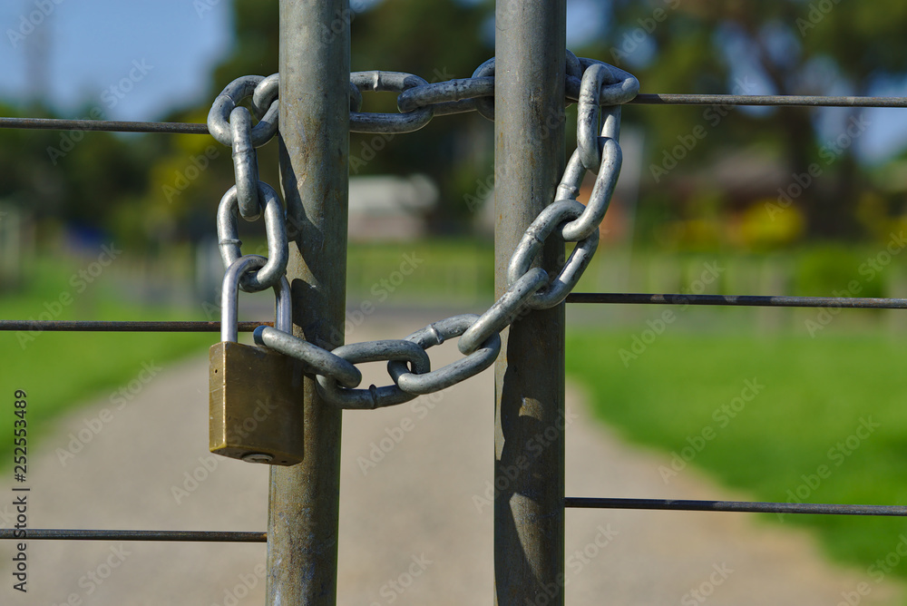 Silver colored chain locked with brass padlock Silver colored chain locked with brass padlock