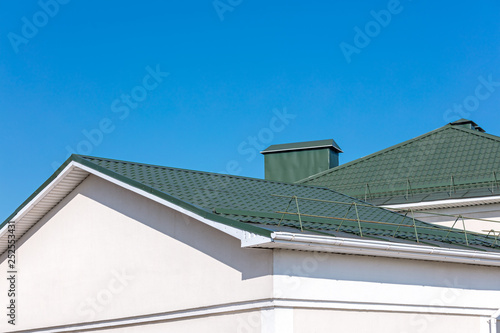 rooftop of house with new rain gutter system against blue sky background