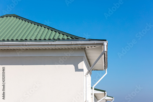 rain gutter system with downspouts on rooftop of renovated house