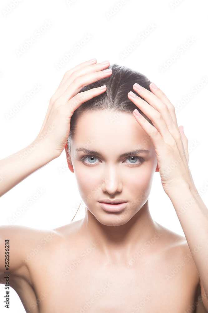 Naklejka premium Beautiful face of young caucasian brunette woman with natural lips, make-up and blue eyes isolated on white. Touch her perfect skin. Studio portrait