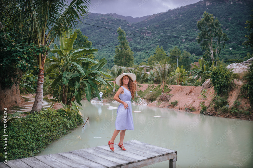 girl in a hat and dress in the jungle by the lake