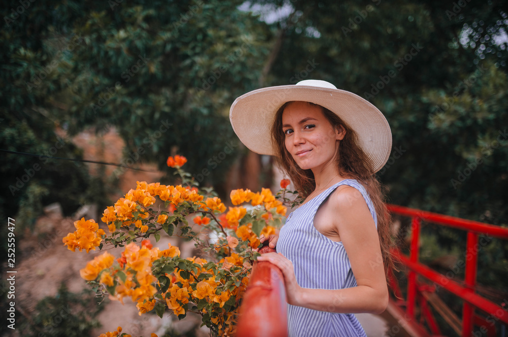 girl in a hat and dress next to yellow flowers