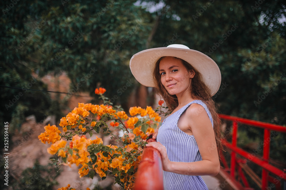 girl in a hat and dress next to yellow flowers
