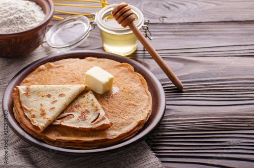 French crepes with butter flour and honey in ceramic dish on wooden kitchen table