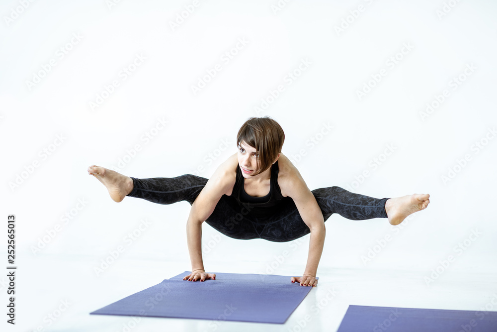 Young woman in black sportswear standing in yoga pose in the white studio Young woman in black sportswear standing in yoga pose in the white studio
