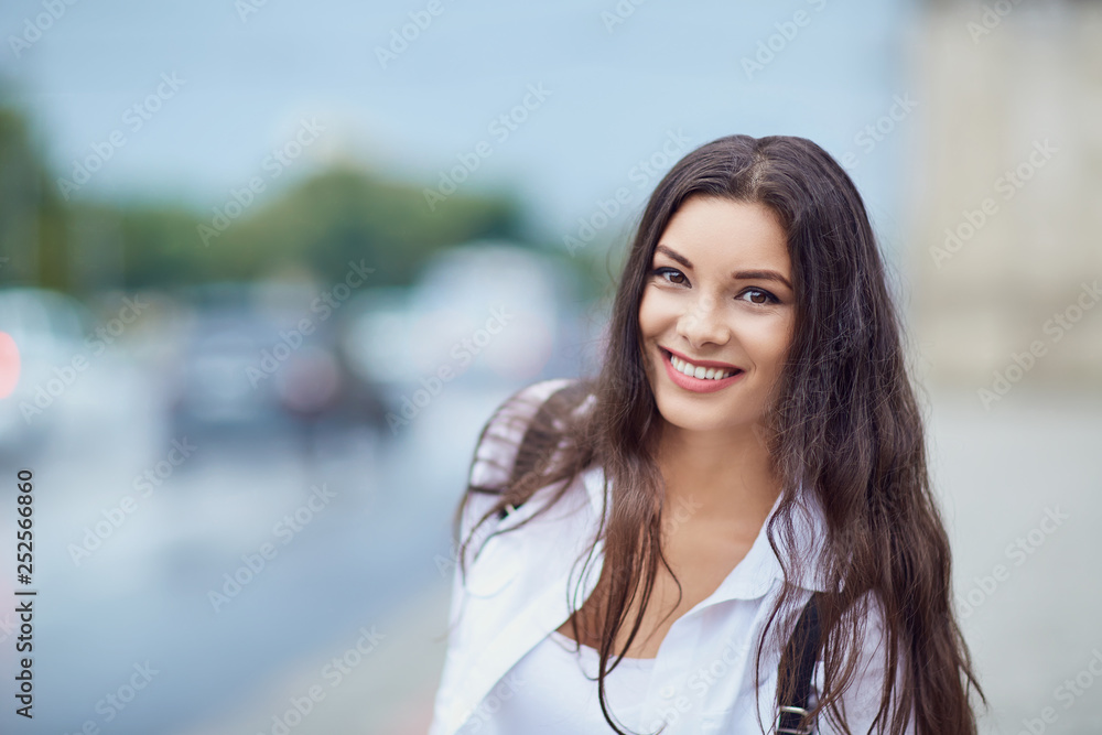 Beautiful happy brunette woman smiling outdoors on city street. 