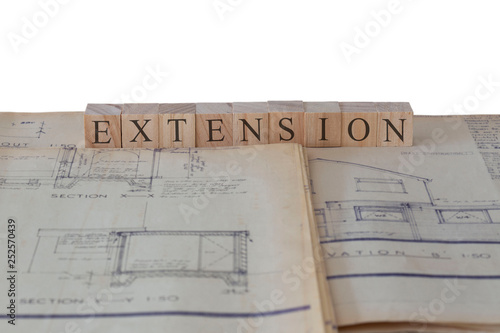 Extension written on wooden blocks on house extension building plans blueprints with a white background