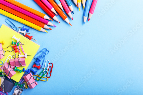 Colored pencils, paper clips and pins, school supplies for drawing, pattern, copy space.