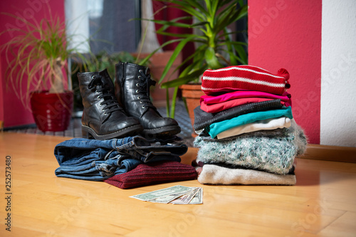 pile of second hand clothing and shoes with money on floor © Firma V