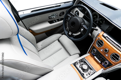 Modern luxury car white leather interior with natural wood panel. Part of leather car seat details with stitching. Interior of prestige modern car. White perforated leather. Car detailing. Car inside © Aleksei