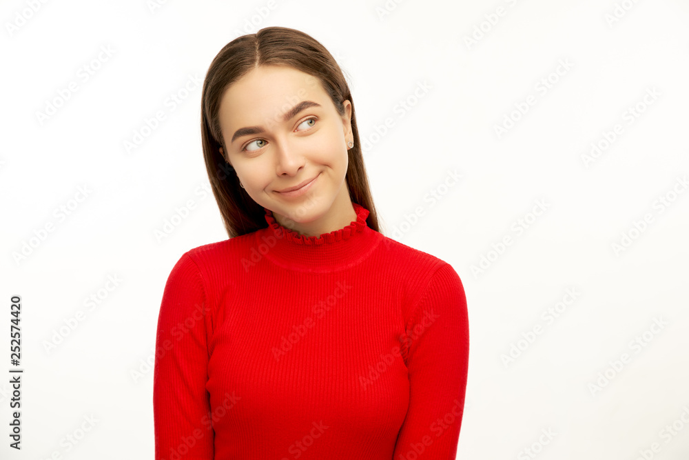Intriguing young woman, looks mysteriously aside, has brilliant idea in mind. Fomale poses against white studio background with free space for your advertising content Intriguing young woman, looks mysteriously aside, has brilliant idea in mind. Fomale poses against white studio background with free space for your advertising content