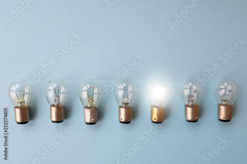 .Row of switched off light bulbs with one switched on. Concept of having idea and creativity