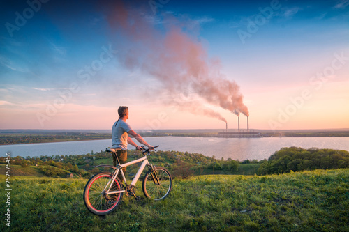 Man with bicycle looking to the power station photo