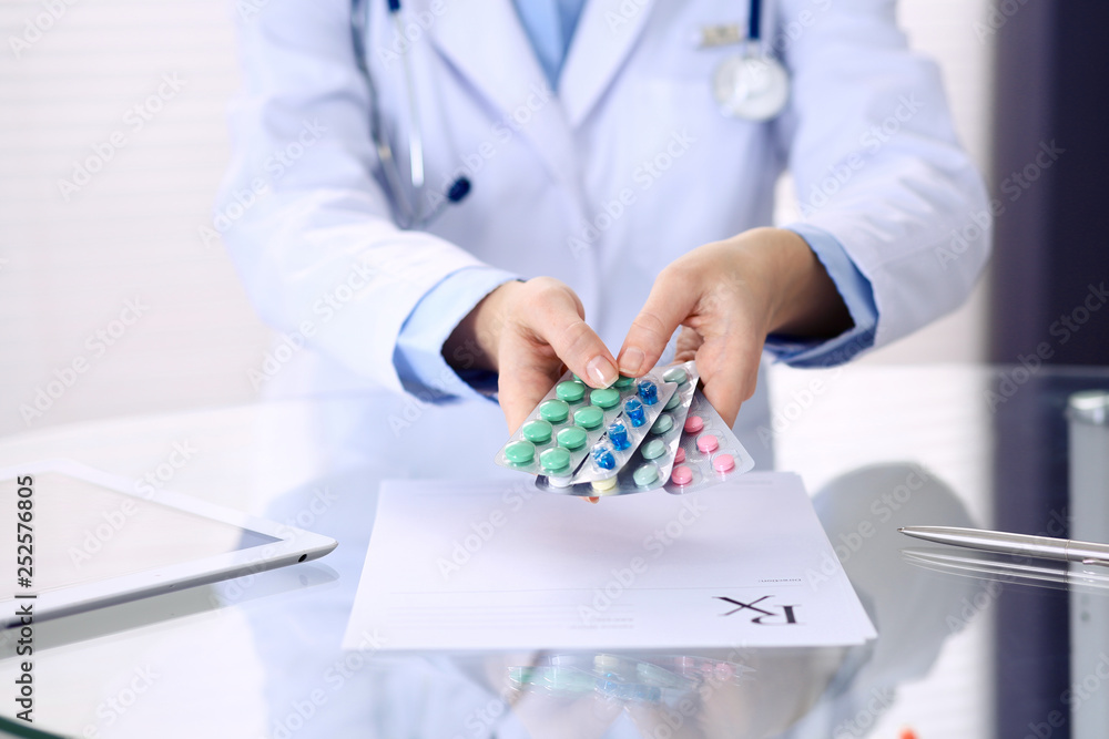Unknown doctor hands holding pack of different tablet blisters closeup. Life save service, legal drug store, prescribe medication, disease healing concept Unknown doctor hands holding pack of different tablet blisters closeup. Life save service, legal drug store, prescribe medication, disease healing concept
